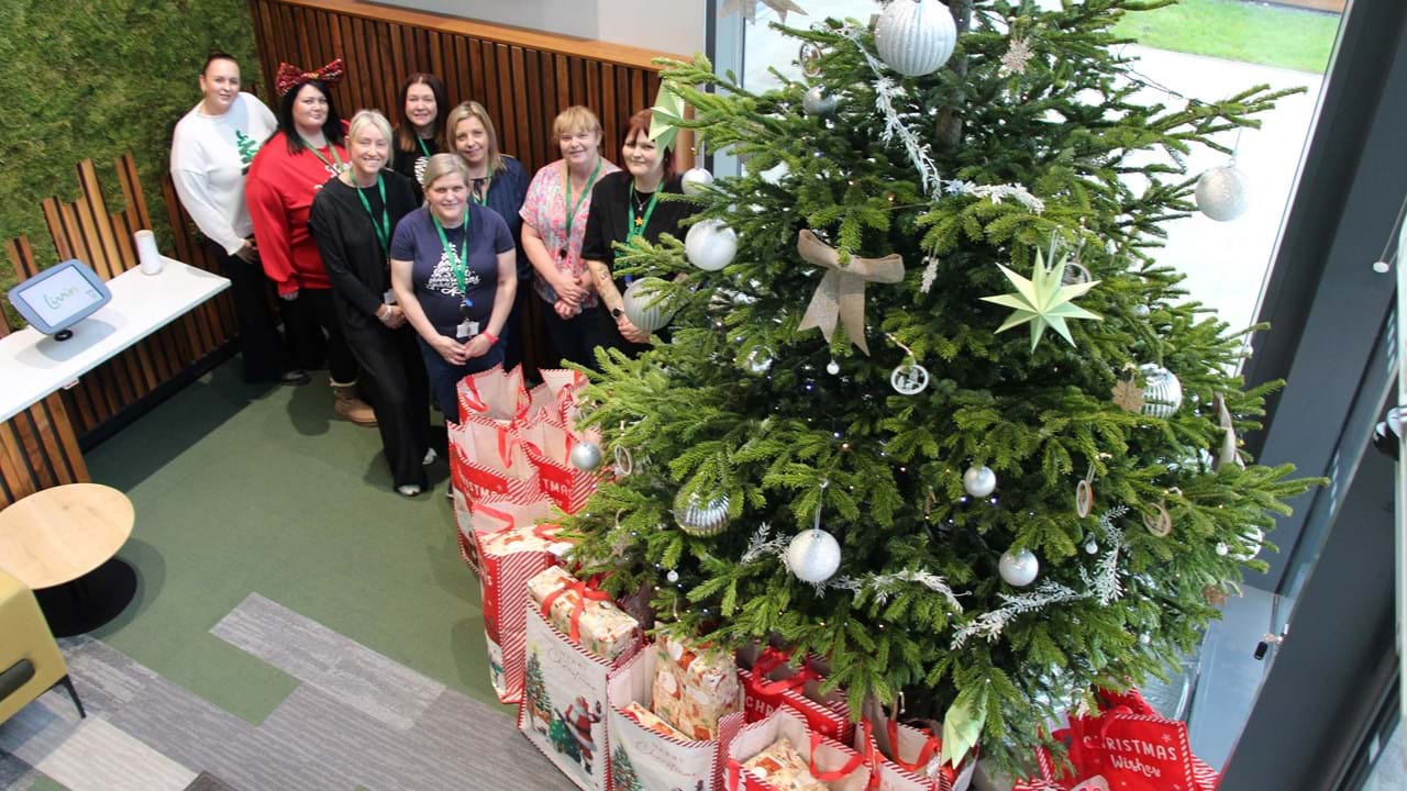 Livin and Mears employees around a Christmas tree with presents