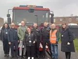 Western community group standing in front of a fire engine