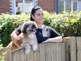 A tenant standing at her fence holding a dog